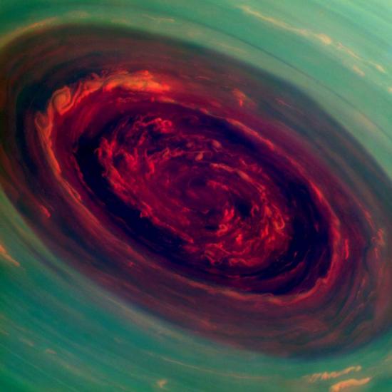 A circular vortex with dark and bright reds at the center surrounded by a light green-blue on its edges.