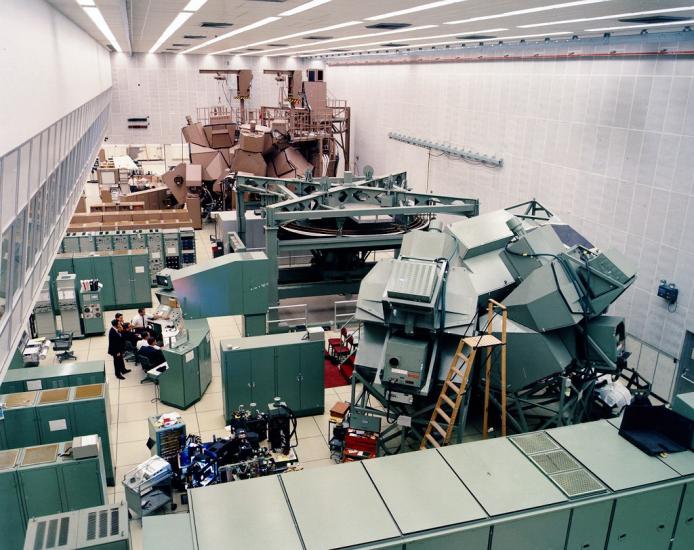 A large room with two inclosed dome-like structures inside. The one closer to the camera is green, the one father is brown.