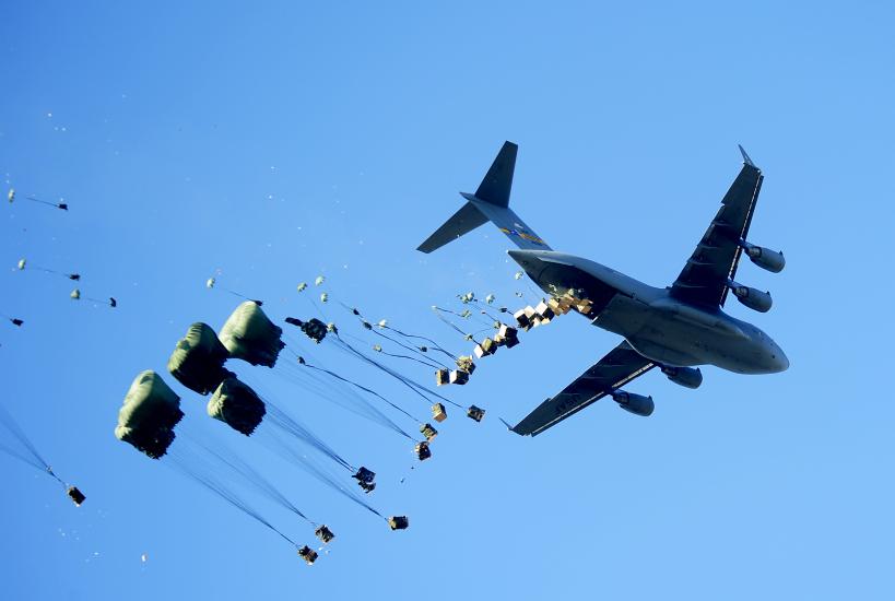 A plane airdropping a number of packages. 