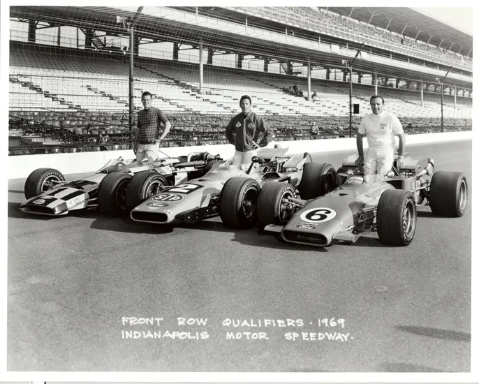 Three men standing behind their Indy 500 race cars.