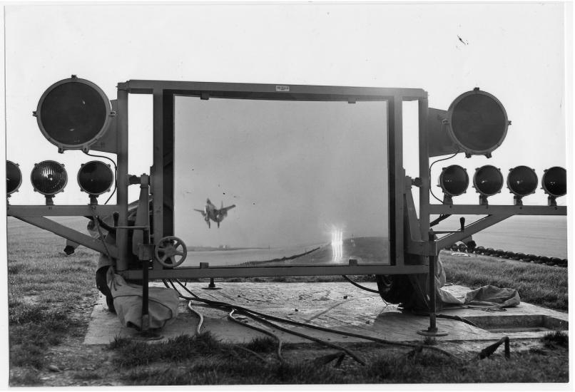 Black and white image of a mirror on a carrier ship with an aircraft in its reflection