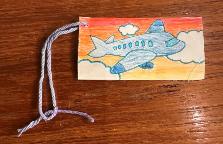 A homemade luggage tag with a drawn on airplane. 