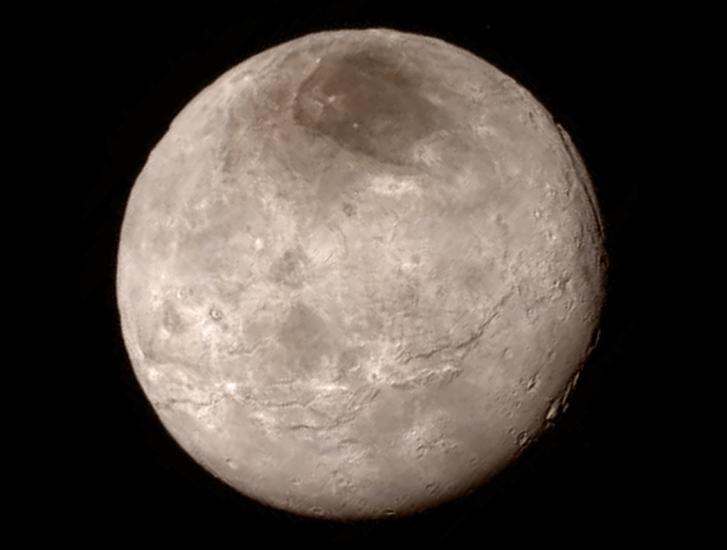 Disk view of Charon, one of Pluto's moons, which has a gray and brown color.