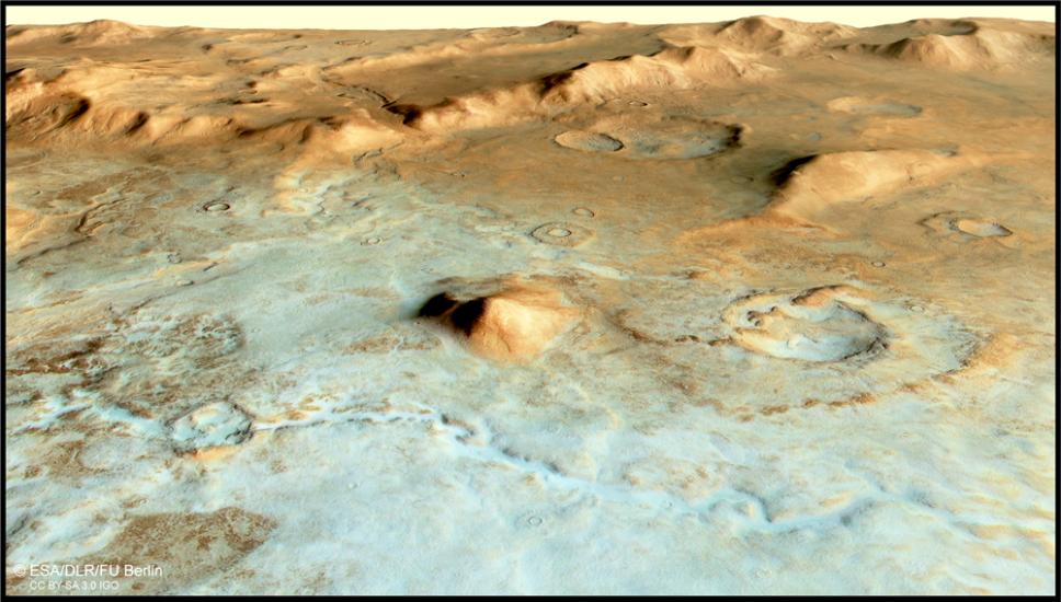 A view of mars surface. Mounds and valleys can be seen. In the forefront of the image the surface is a blueish green color and shifts to brown toward the background of the image.