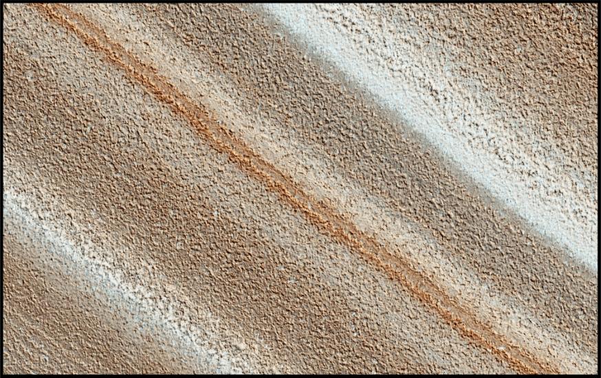 An image of mars surface showing stripes of different hues of reds, oranges, browns, and whites.