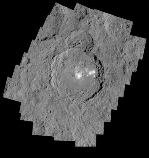 A view of the rough surface of Ceres with a cluster of white spots at the center of a crater.