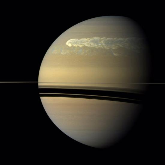 A view of Saturn with a strip of swirling clouds running across the top.