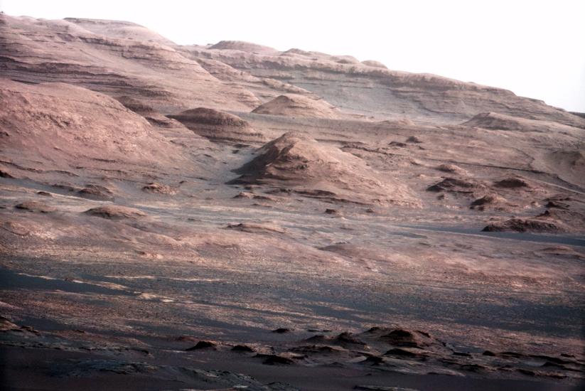 Jagged rocks on Mars jut out of the ground, each demonstrating their layered history through different bands of colors.