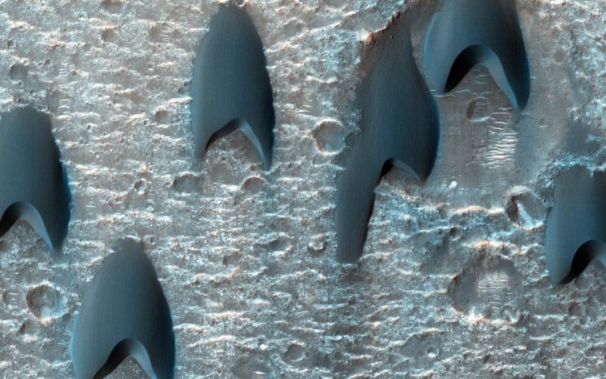 Arrowhead shaped dark splotches cover the cratered surface of Mars.