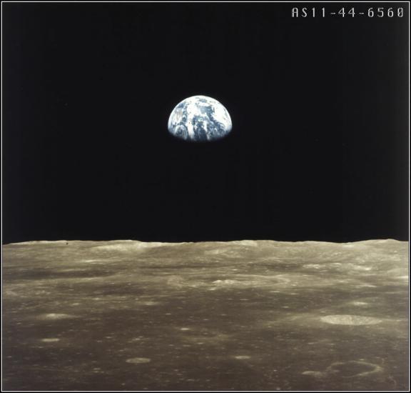 An image taken from the surface of the Moon looking toward Earth. The bottom one-fourth of the Earth is shrouded in darkness.