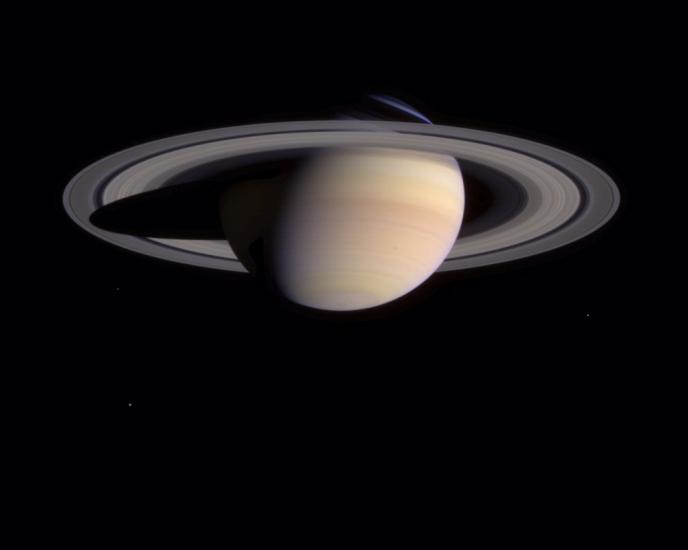 Saturn as seen from the bottom half up. A spot can be seen on the bottom left of the planet.