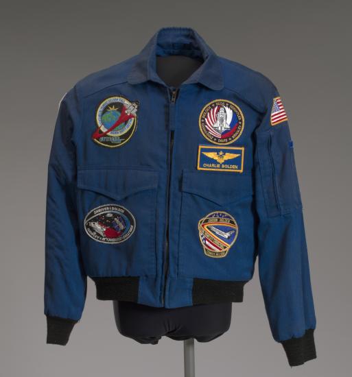 A blue NASA flight jacket covered in various mission patches.