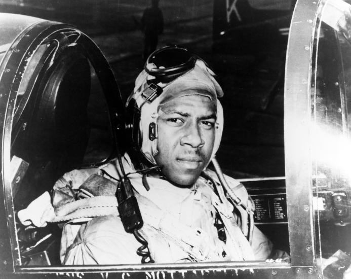 Jesse Leroy Brown looks toward the camera as he sits at the controls of an aircraft.