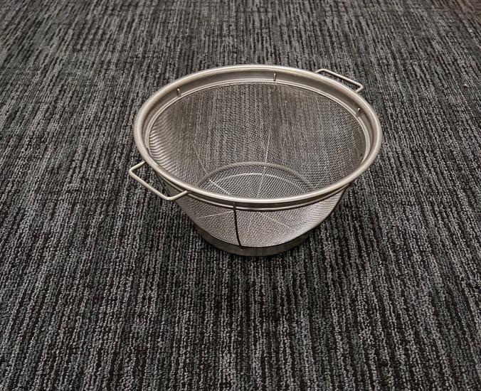 A colander sitting on carpet.