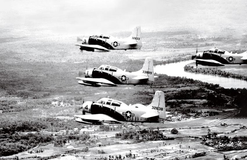 A black and white photograph showing four Douglas A1E Skyraiders, small aircraft, flying in formation over Vietnam.