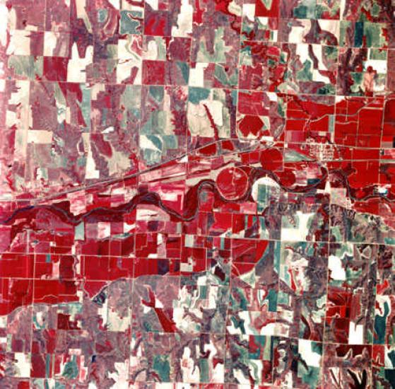 An aerial photo looking down at land, which looks red and green colored and split into irregular squares.