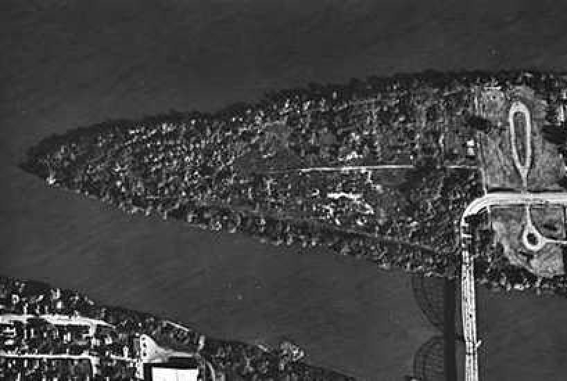 An aerial photo of a triangular shaped island that has a bridge connecting it to the mainland.