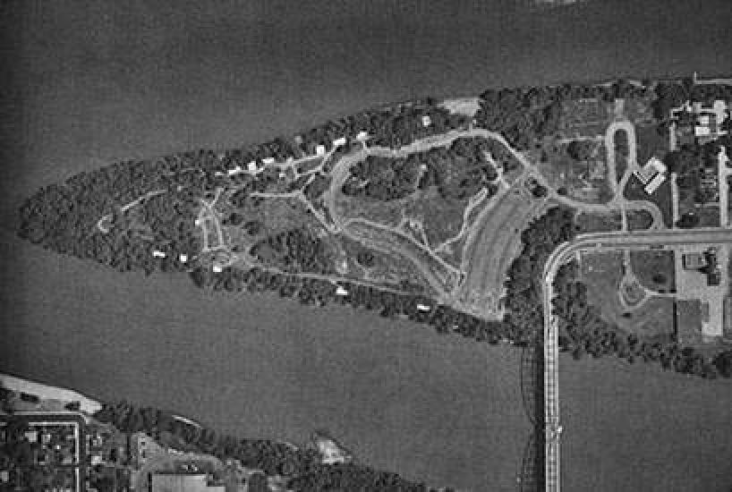 An aerial photo of a triangular shaped island that has a bridge connecting it to the mainland.