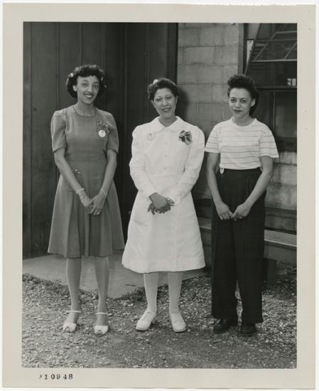 Three women stand outside a building