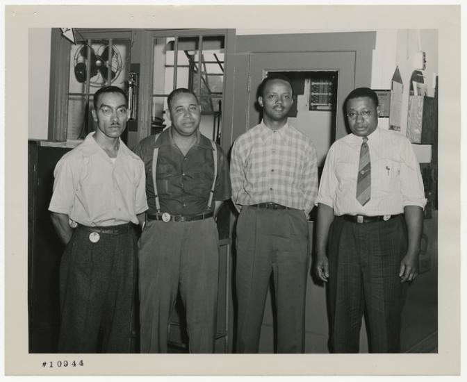 Four men stand inside an industrial building