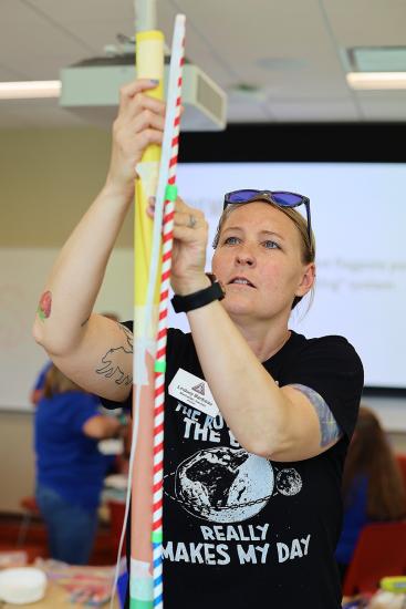 A woman in a black tee shirt constructs a small tower. 