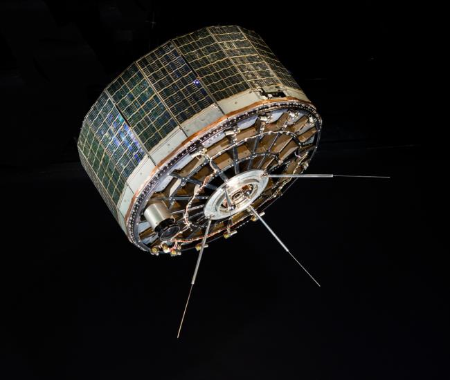 A stout cylindrical satellite with panels on the outside. 