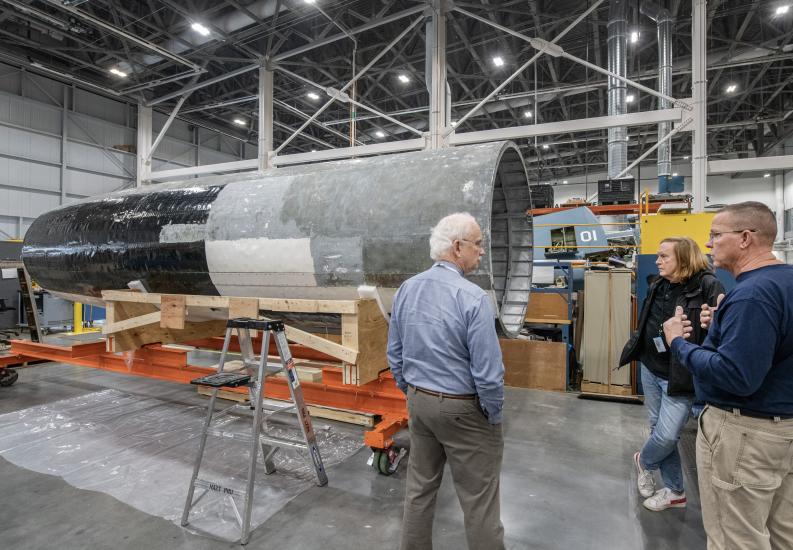 The individuals having a discussion in a restoration hangar.