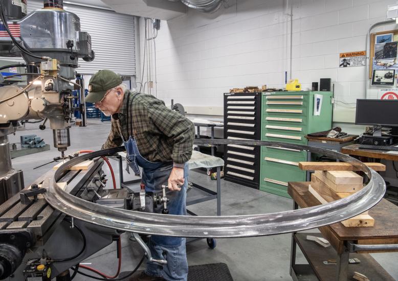 A man works on a large circular rocket part.