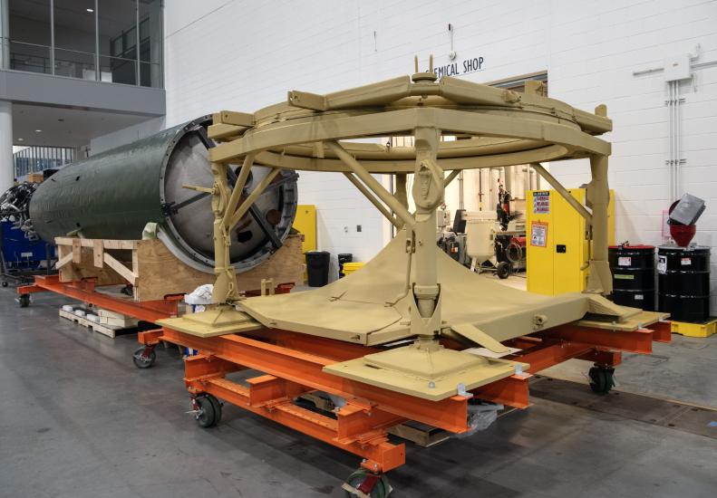 Center section of V2 rocket is attached to a launch table in a restoration facility.