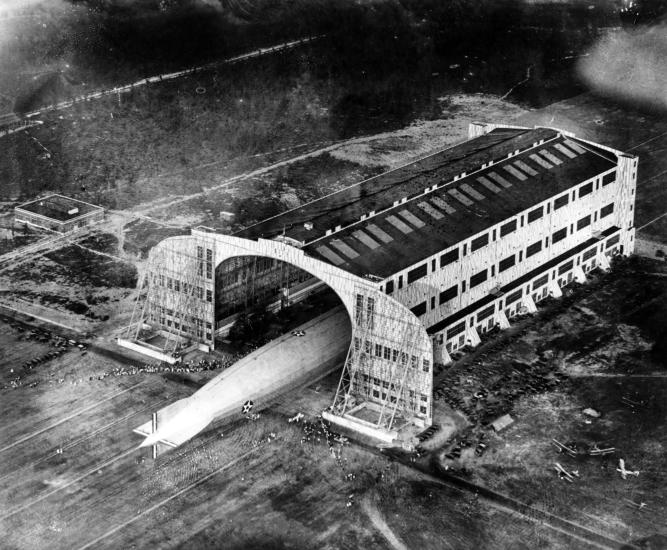 A view of the back half of Shenandoah from above as it is pulled out of its hangar. Hundreds of people can be see from the ground.