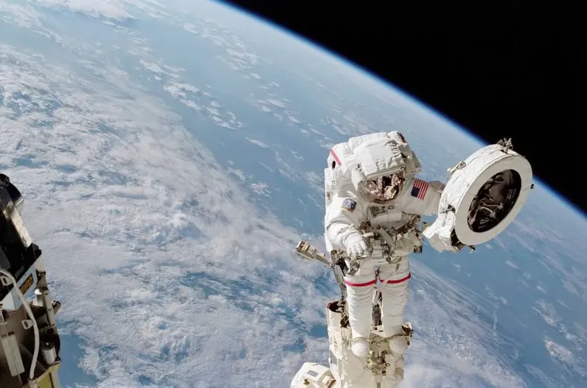 An astronaut works on the exterior of the International Space Station. A portion of the Earth is visible behind him.