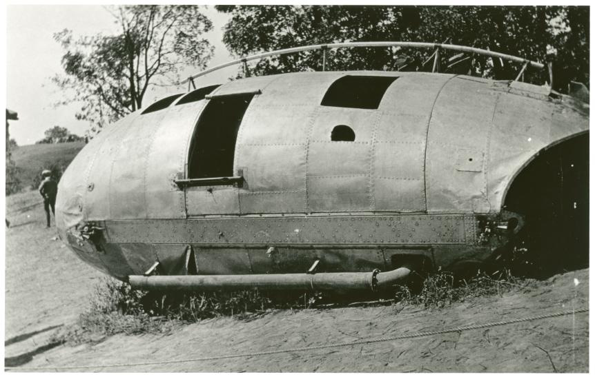 An oblong metal structure that has crashed into the tree line.