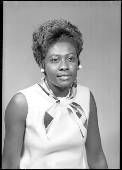 A black and white photograph of a Black woman in 1960s attire.