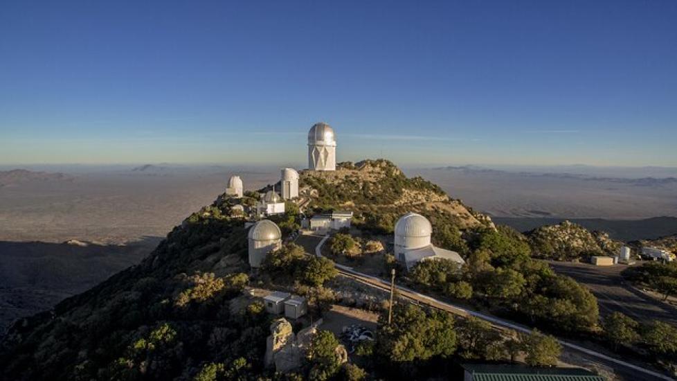 : Eight white buildings located on top of a mountain - six of them have domed tops while the other have regular pitched roofs. 