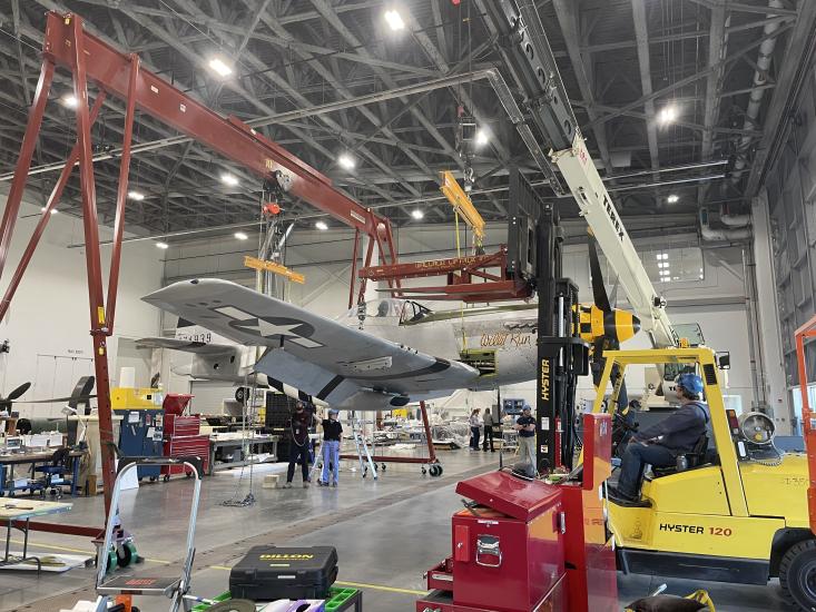 An aircraft is lifted by a machine in an interior location.