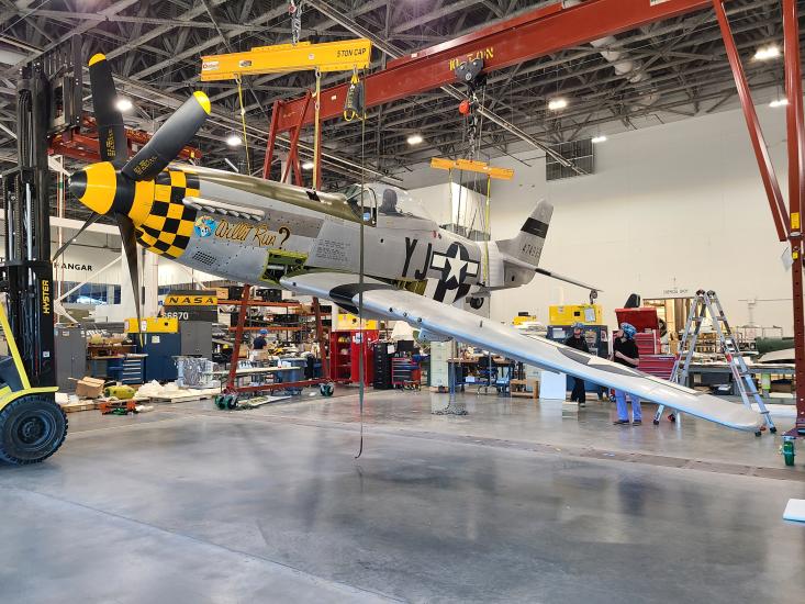 An aircraft hangs from the ceiling in an interior room under construction.