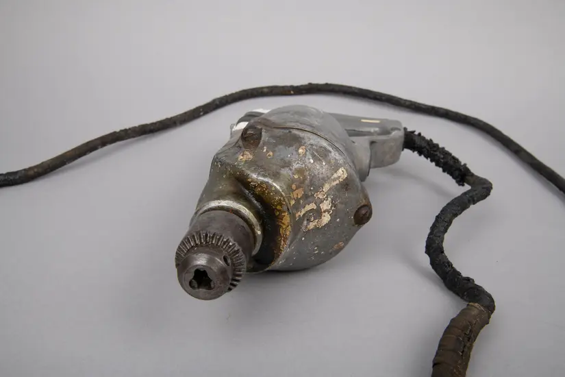 Closeup of a metal drill against a grey backdrop.