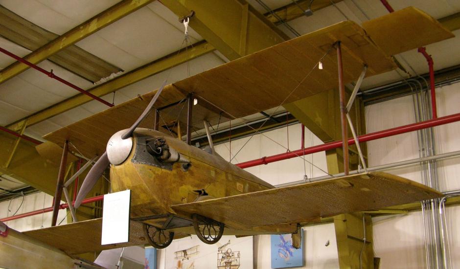 K-III airplane hangs from the ceiling inside a facility.