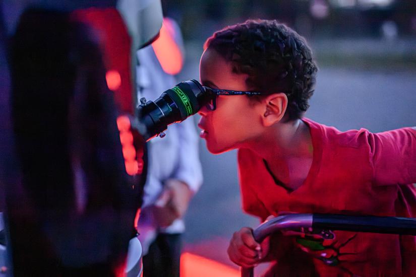 A young visitor looks through a telescope eyepiece