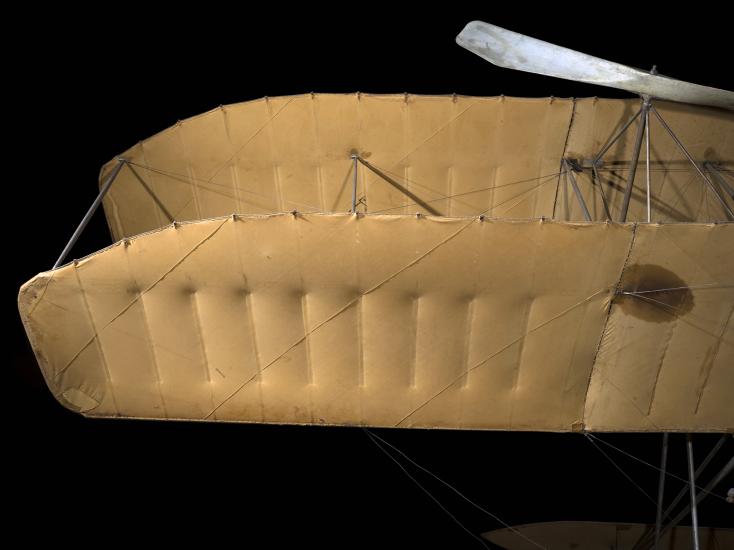 Closeup of a vintage biplane's starboard wings, on a black background.