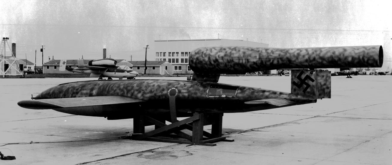 Vintage black and white image of a missile as it lays horizontally at an airfield.