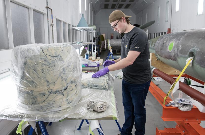 A person inspecting components of a missile in a restoration hangar.