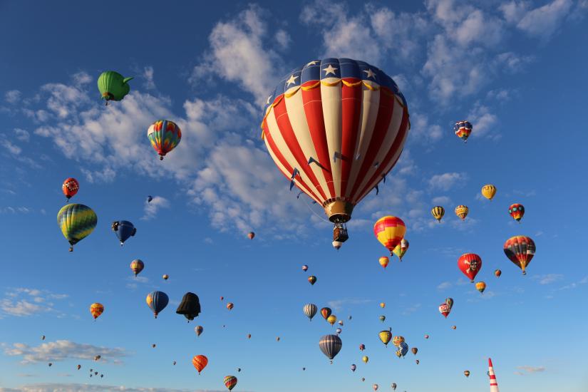 Colorful hot air balloons fill a bright blue sky.