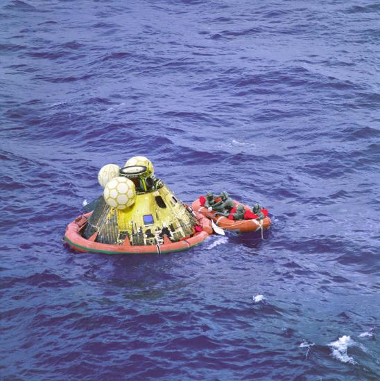 Apollo 11 command module in the ocean with recovery crew attached. 