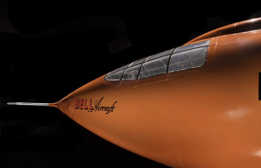 Side view of nose of an aircraft. The aircraft is painted orange. 