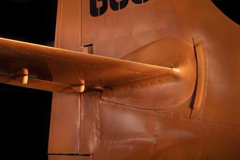 Close up of vertical and horizontal stabilizer of an aircraft. The aircraft is painted orange. 