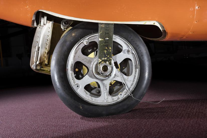  View of a tire on an aircraft. The aircraft is painted orange. 