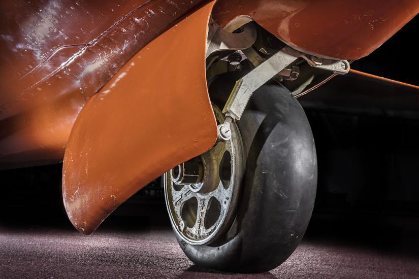 View of a tire on an aircraft. The aircraft is painted orange. 