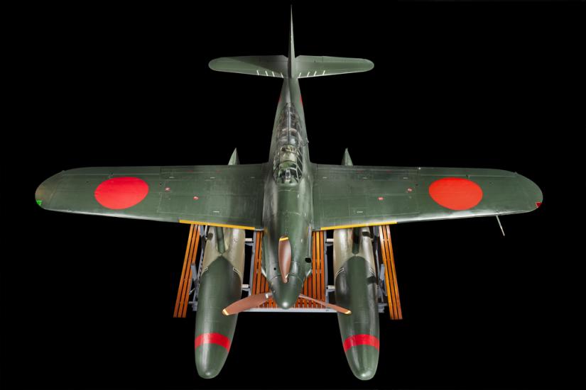 Above view of a green bomber with red roundels on the wings and twin floats in place of wheels.