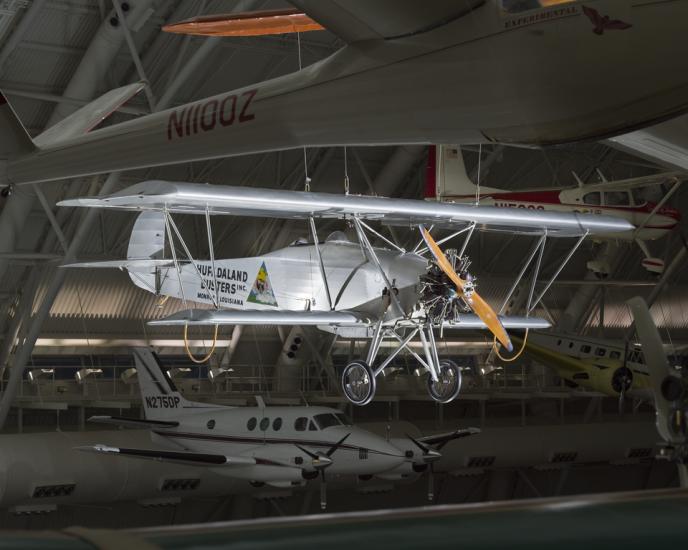 Silver painted biplane with wood propellers. Huff-Daland Duster is painted on the side of the plane.